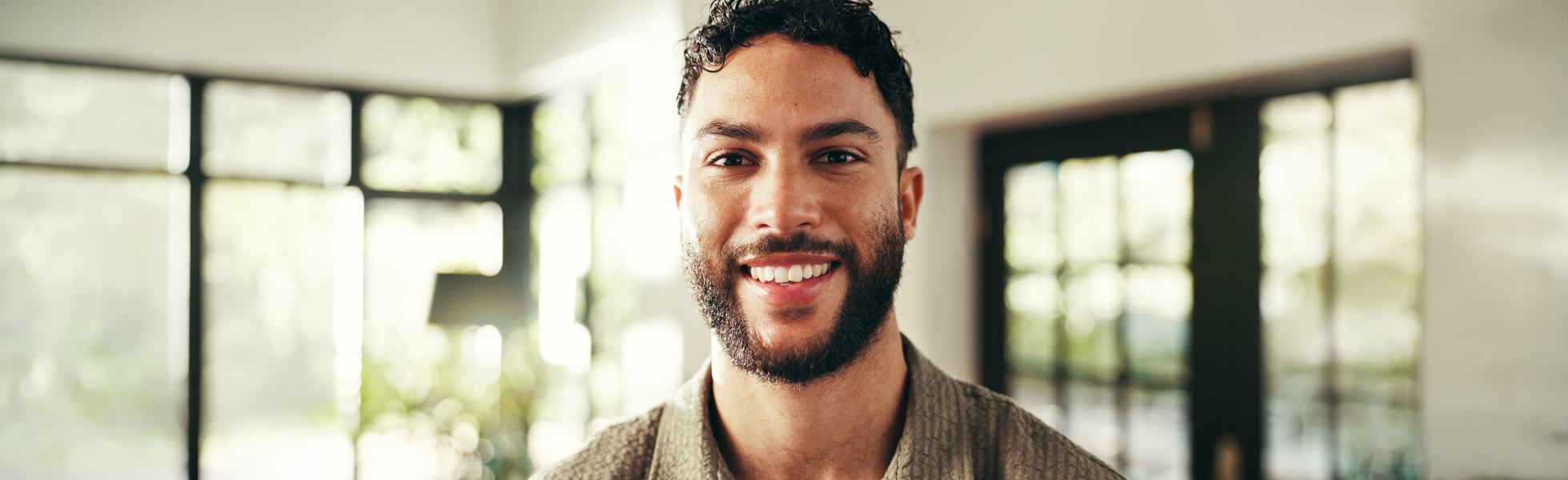Smiling man with a beard in a bright indoor setting, representing male fertility and wellness.