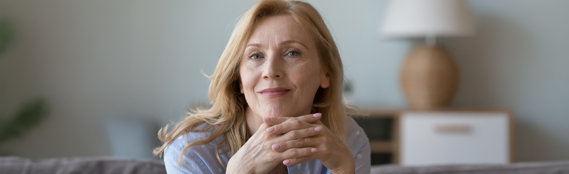 Smiling woman with long hair resting her chin on her hands, conveying a sense of calm and reflection on menopause.