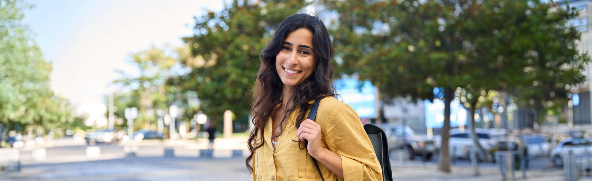 Smiling woman in a yellow shirt stands outdoors, suggesting a positive outlook amidst discussions on pelvic pain.